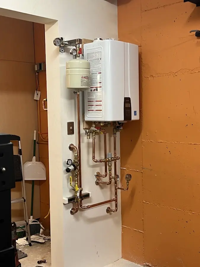 Plumbing technician inspecting water heater connections in Williams